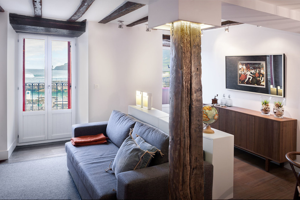 Exemple d'un salon montagne de taille moyenne et ouvert avec une salle de réception, un mur blanc, un sol en bois brun, une cheminée ribbon, un manteau de cheminée en métal et un téléviseur encastré.