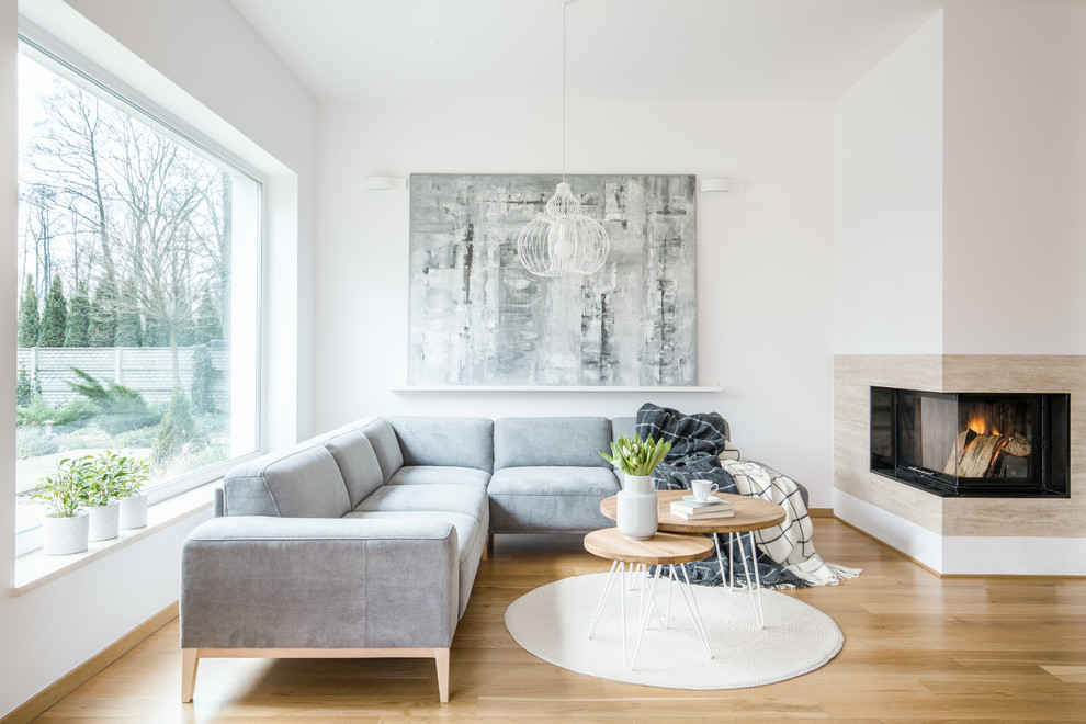 Ispirazione per un soggiorno contemporaneo aperto con pareti bianche, pavimento in legno massello medio, camino ad angolo e pavimento marrone