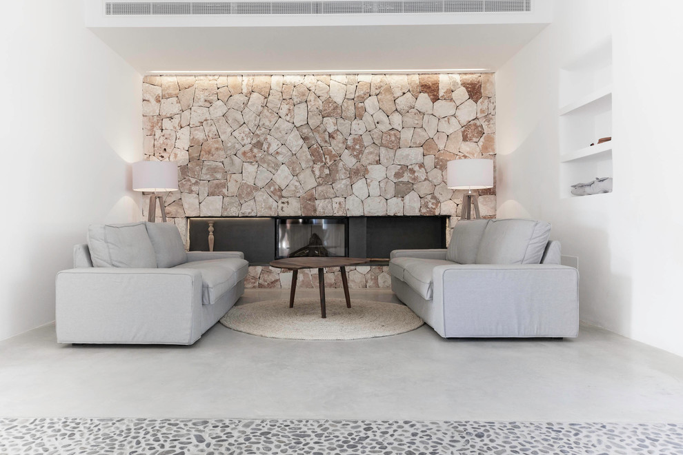 Источник вдохновения для домашнего уюта: парадная, изолированная гостиная комната среднего размера в средиземноморском стиле с белыми стенами, бетонным полом, горизонтальным камином и фасадом камина из камня