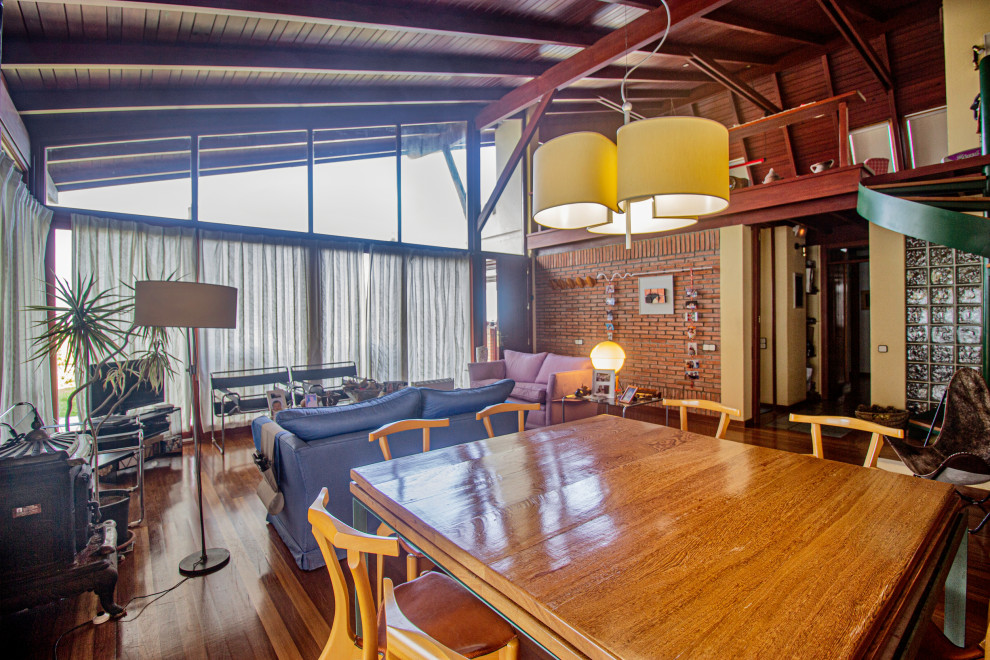 Modelo de salón abierto urbano grande con paredes beige, suelo de madera en tonos medios, estufa de leña, televisor independiente y suelo marrón