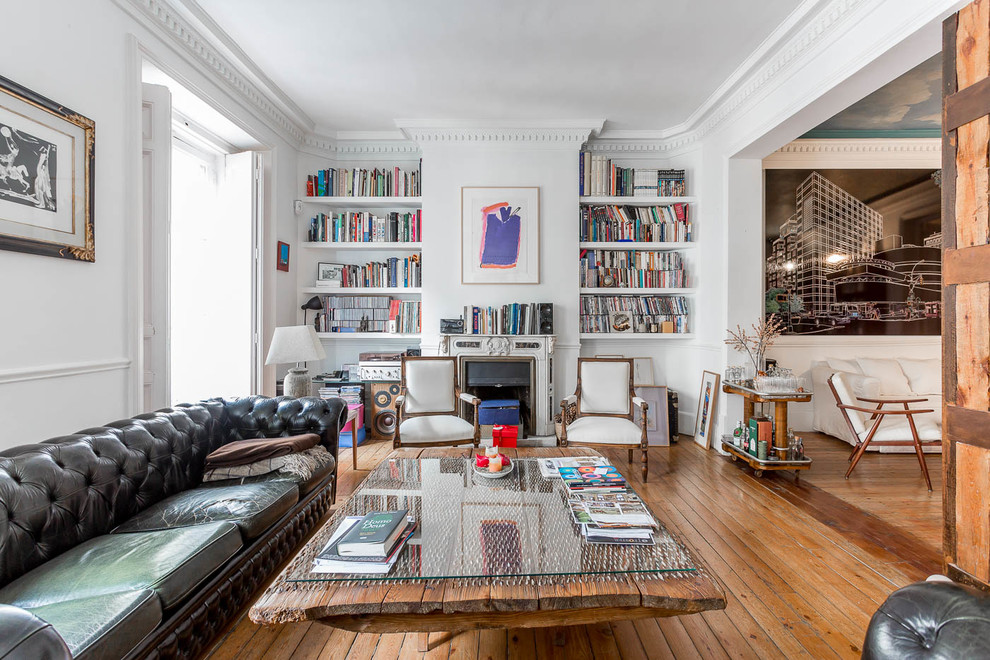 Photo of a large bohemian open plan living room in Madrid with a reading nook, a standard fireplace, white walls, medium hardwood flooring and brown floors.