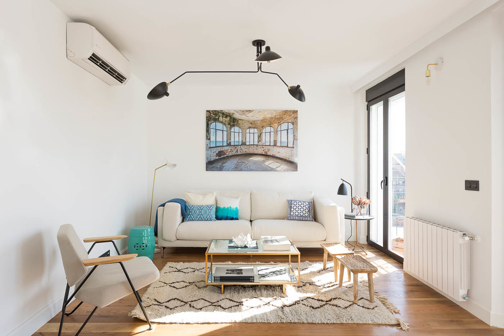 Small classic open plan living room in Madrid with white walls, medium hardwood flooring, no fireplace and brown floors.