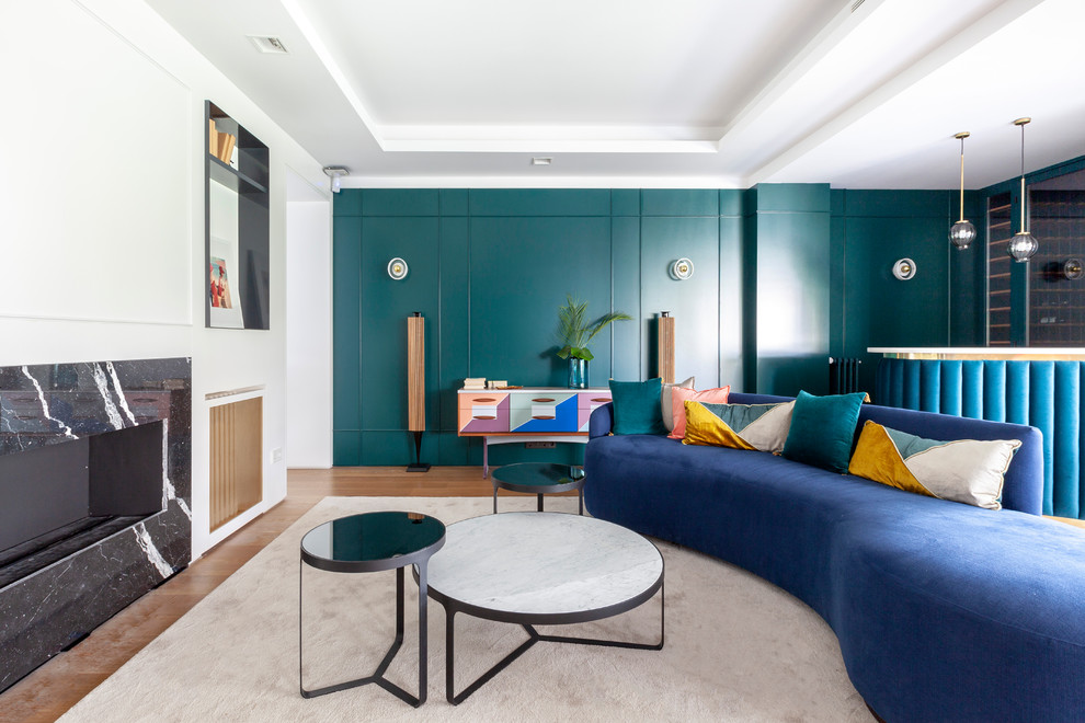 Источник вдохновения для домашнего уюта: гостиная комната в современном стиле с домашним баром, зелеными стенами, паркетным полом среднего тона, горизонтальным камином, фасадом камина из камня, синим диваном и ковром на полу