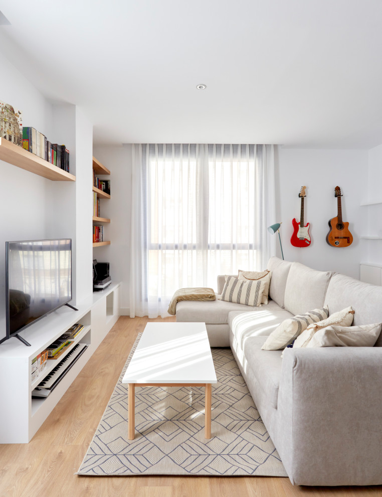 Modelo de salón abierto minimalista grande con paredes blancas, suelo de madera clara y pared multimedia