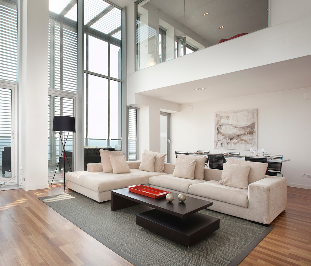 Großes, Repräsentatives, Fernseherloses, Offenes Modernes Wohnzimmer ohne Kamin mit weißer Wandfarbe und braunem Holzboden in Barcelona