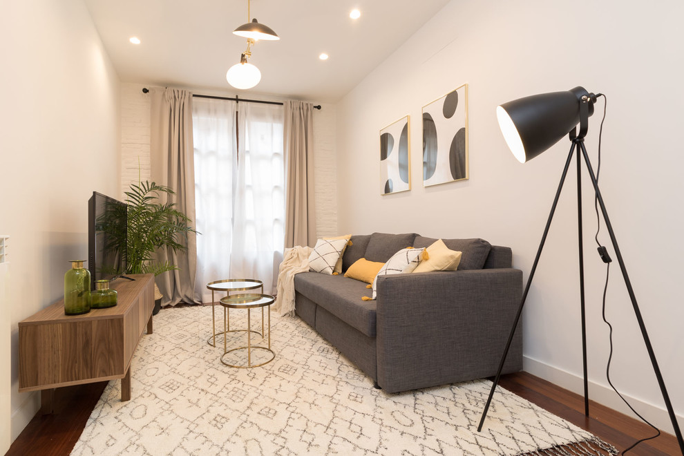 This is an example of a small scandi formal enclosed living room in Other with white walls, dark hardwood flooring, a freestanding tv, brown floors and feature lighting.