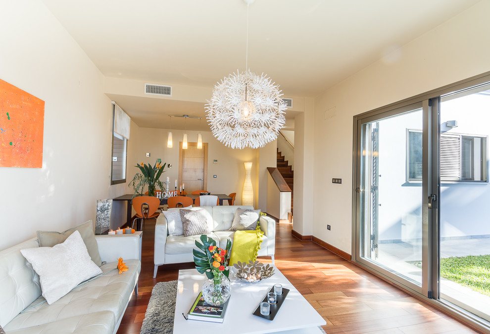 Esempio di un soggiorno mediterraneo di medie dimensioni e aperto con pareti beige, pavimento in laminato, TV autoportante e pavimento marrone