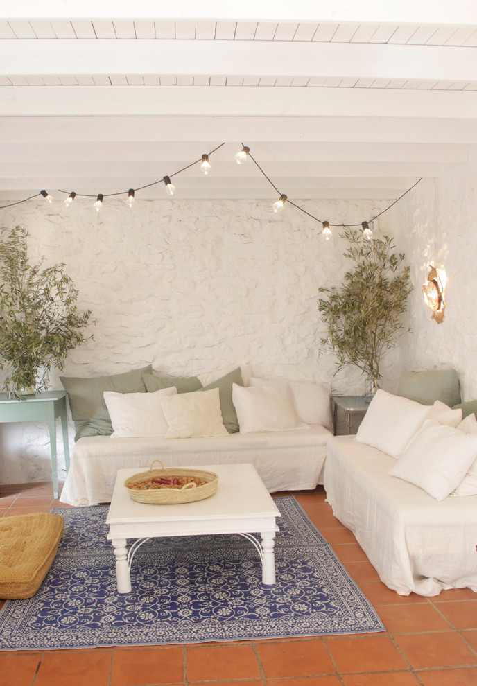 Diseño de salón mediterráneo con paredes blancas, suelo de baldosas de terracota y suelo rojo
