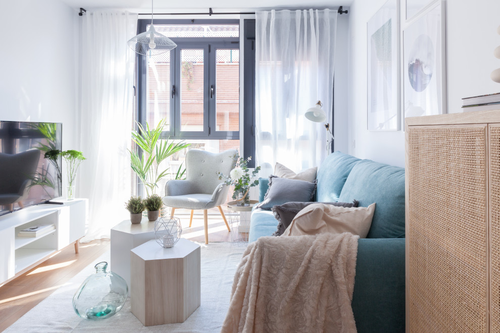 На фото: маленькая открытая гостиная комната в скандинавском стиле с белыми стенами, паркетным полом среднего тона, коричневым полом и отдельно стоящим телевизором для на участке и в саду с