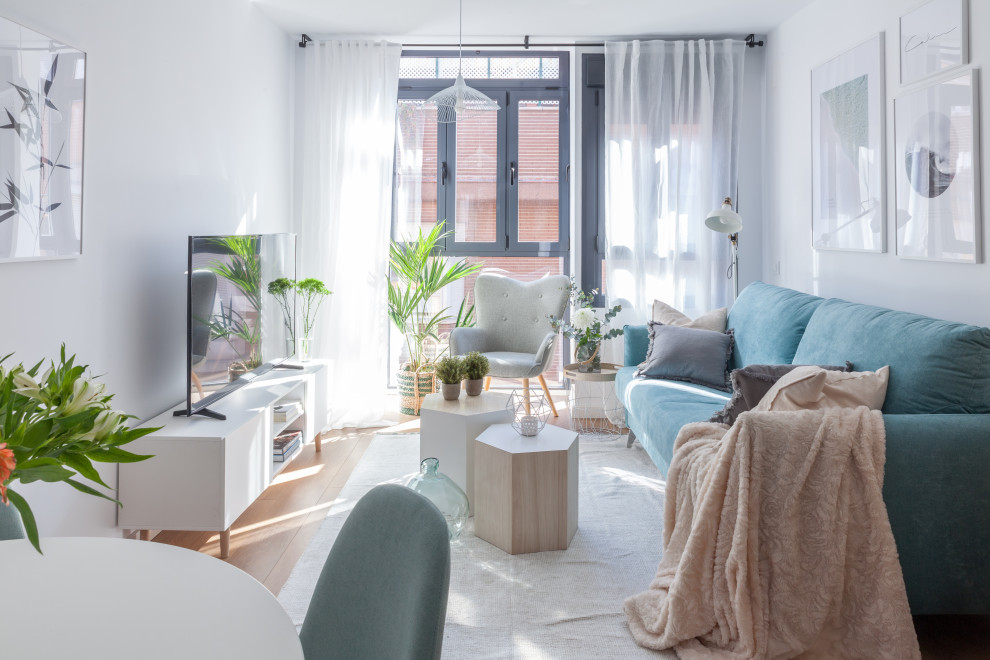 Kleines, Offenes Skandinavisches Wohnzimmer mit weißer Wandfarbe, braunem Holzboden, TV-Wand und braunem Boden in Madrid
