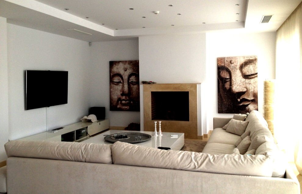 Imagen de salón para visitas cerrado tropical de tamaño medio con paredes blancas, todas las chimeneas y televisor colgado en la pared