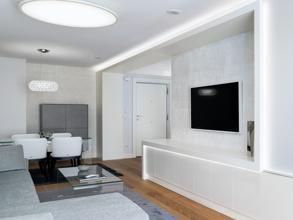 Inredning av ett modernt litet separat vardagsrum, med vita väggar, mellanmörkt trägolv, en väggmonterad TV och brunt golv
