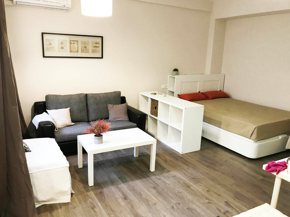 Ejemplo de salón tipo loft contemporáneo pequeño con paredes beige, suelo laminado, televisor colgado en la pared y suelo marrón