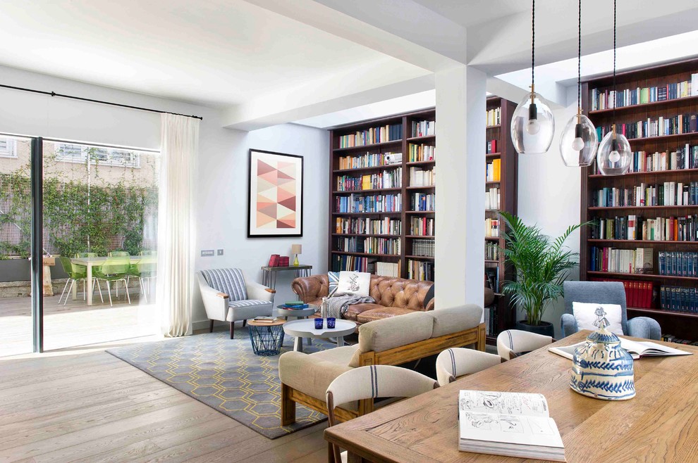 Ejemplo de biblioteca en casa abierta actual extra grande con paredes blancas, suelo de madera clara y suelo beige