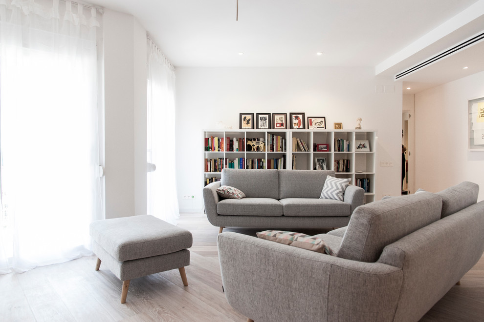 Ejemplo de biblioteca en casa abierta escandinava de tamaño medio sin chimenea y televisor con paredes blancas y suelo de madera en tonos medios