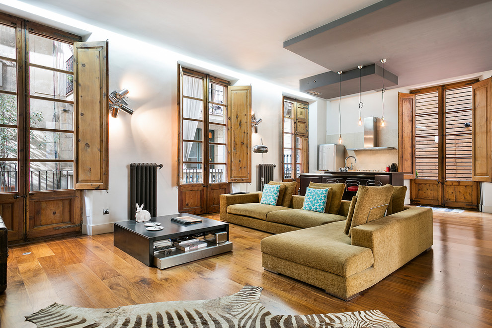 Mittelgroßes, Repräsentatives, Fernseherloses, Offenes Industrial Wohnzimmer mit weißer Wandfarbe und braunem Holzboden in Barcelona