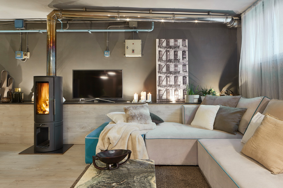 Foto de salón urbano con paredes grises, suelo de madera clara, televisor independiente y suelo beige