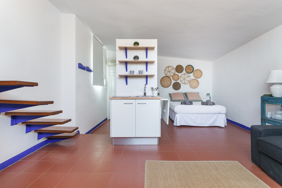 Diseño de salón tipo loft costero de tamaño medio sin chimenea con paredes blancas, suelo de baldosas de terracota y suelo rojo