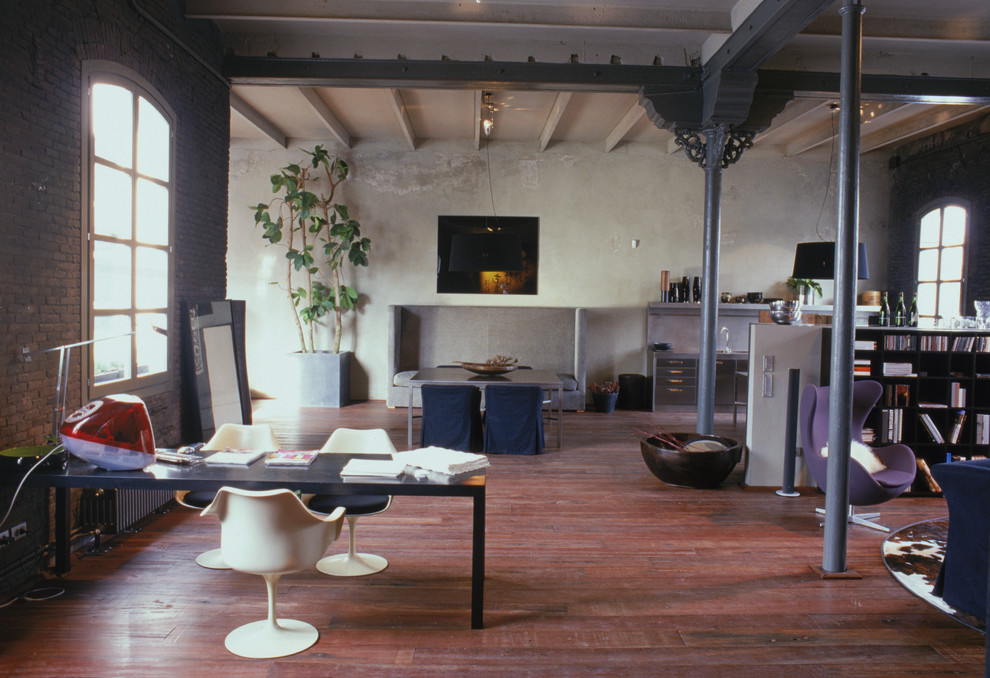 Cette image montre un grand salon mansardé ou avec mezzanine urbain avec parquet foncé, une salle de réception et un mur marron.