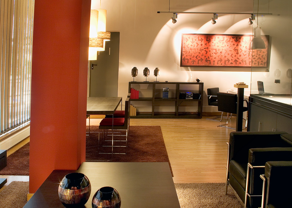 Imagen de salón minimalista con paredes rojas, suelo de madera en tonos medios y suelo beige