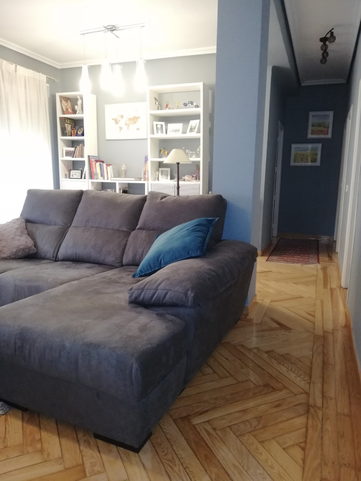 Foto de biblioteca en casa abierta bohemia de tamaño medio sin chimenea con paredes azules, suelo de madera clara, televisor independiente y suelo marrón