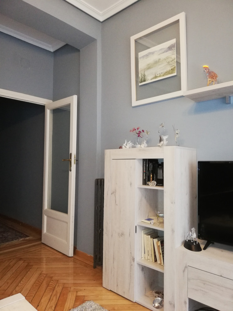 Ejemplo de salón abierto tradicional renovado de tamaño medio sin chimenea con paredes azules, suelo de madera clara, televisor independiente y suelo marrón