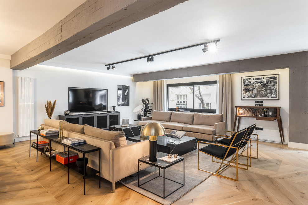 Diseño de salón abierto escandinavo con paredes grises, suelo de madera clara, televisor independiente y suelo beige