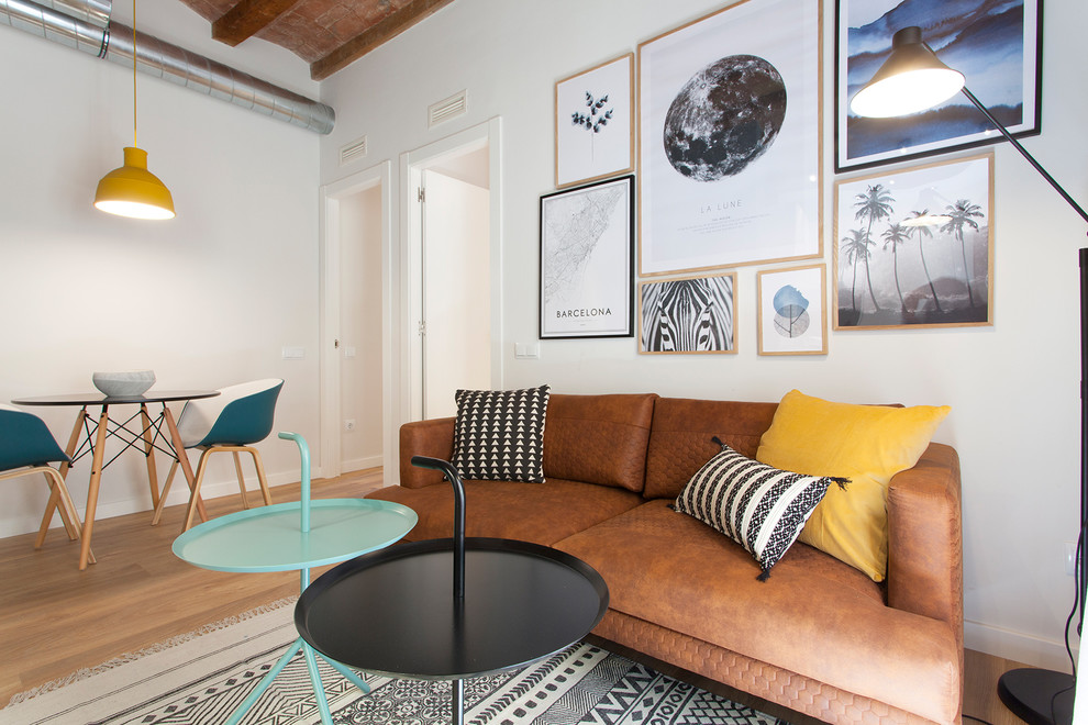 Kleines, Offenes Nordisches Wohnzimmer ohne Kamin mit braunem Boden, weißer Wandfarbe und hellem Holzboden in Barcelona