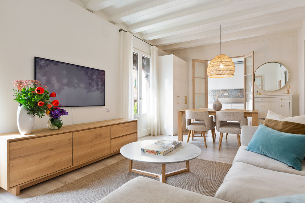 Imagen de salón abierto mediterráneo pequeño con paredes blancas, suelo de madera clara y televisor colgado en la pared