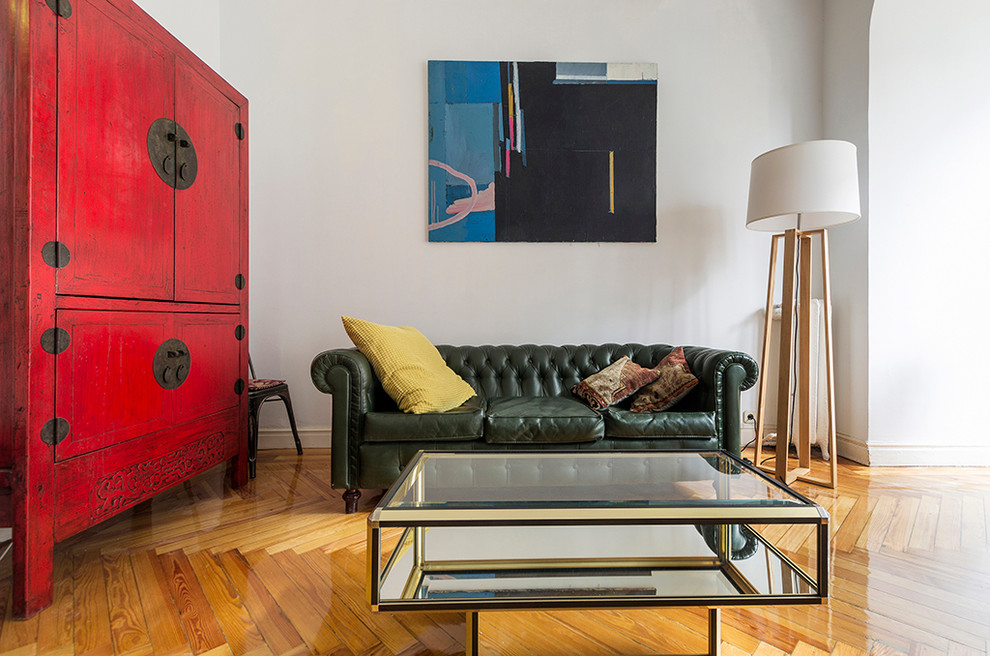 This is an example of a medium sized eclectic formal enclosed living room in Madrid with white walls, medium hardwood flooring and no fireplace.