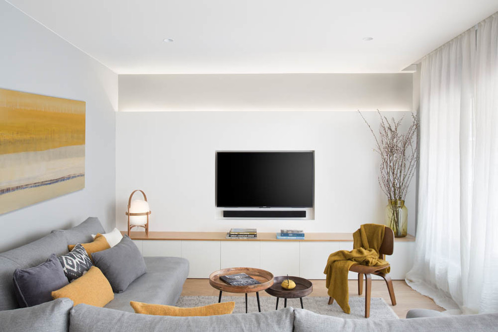Modern inredning av ett mellanstort allrum med öppen planlösning, med ett finrum, vita väggar, mellanmörkt trägolv och en väggmonterad TV