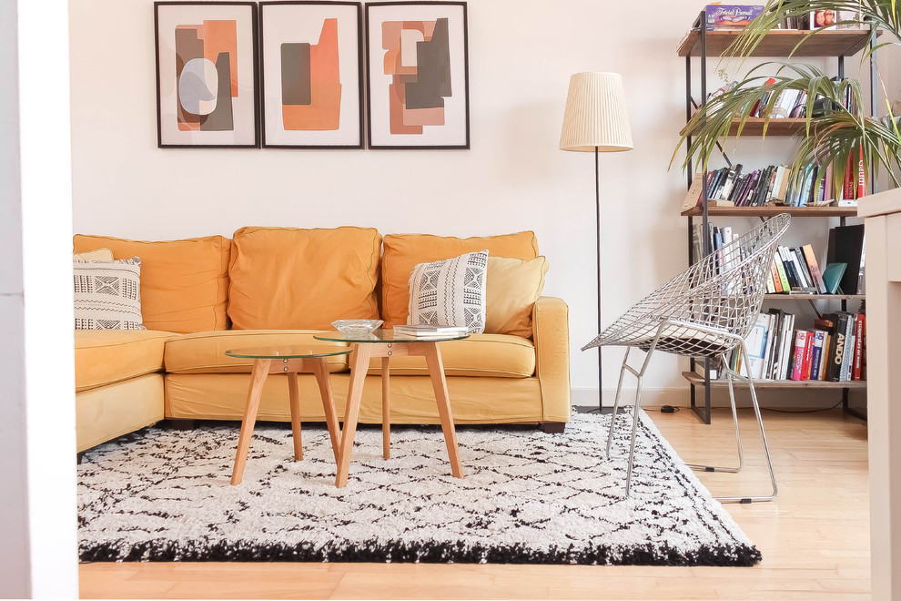 Foto di un soggiorno design di medie dimensioni con libreria, pareti bianche, parquet chiaro e pavimento beige