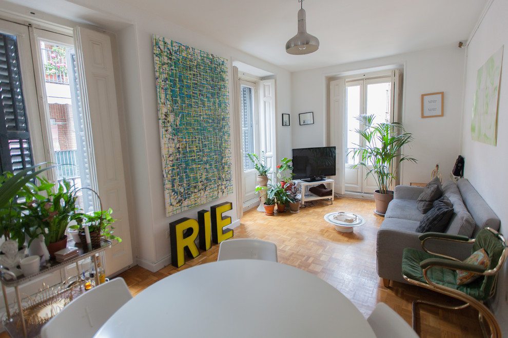 Mittelgroßes, Repräsentatives, Offenes Stilmix Wohnzimmer ohne Kamin mit weißer Wandfarbe, freistehendem TV und hellem Holzboden in Madrid