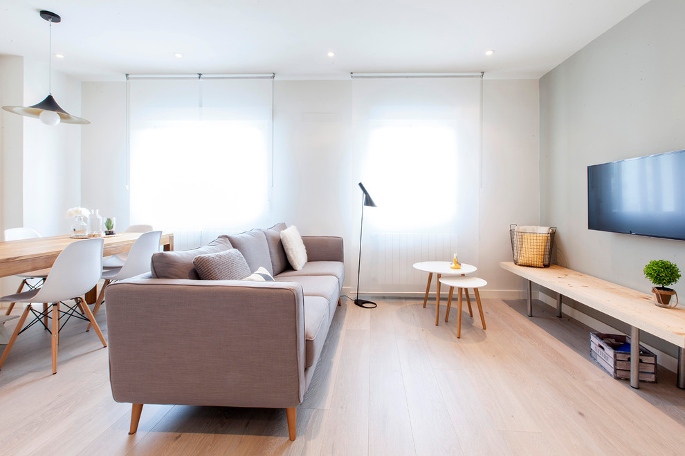 Diseño de salón para visitas cerrado nórdico de tamaño medio sin chimenea con paredes blancas, suelo de madera clara y televisor colgado en la pared