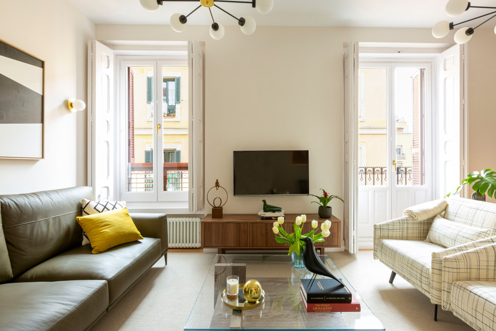 This is an example of a formal open plan living room in Madrid with white walls, medium hardwood flooring and a wall mounted tv.