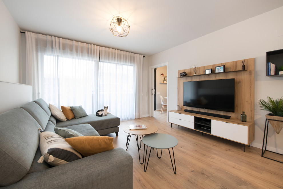 Diseño de salón cerrado nórdico grande sin chimenea con paredes grises, suelo de madera en tonos medios, televisor colgado en la pared y suelo beige