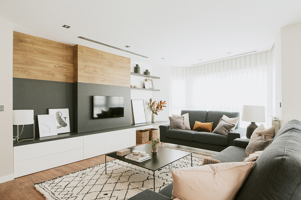 Immagine di un soggiorno minimal con pareti bianche, pavimento in legno massello medio, TV a parete e pavimento marrone