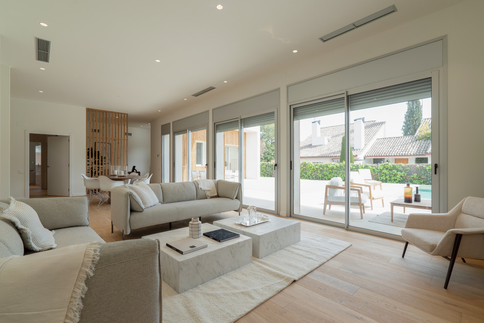 Diseño de salón abierto contemporáneo grande sin televisor con paredes blancas, suelo de madera clara y suelo beige