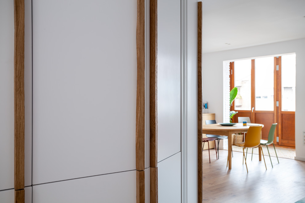 На фото: гостиная комната среднего размера в скандинавском стиле с белыми стенами, паркетным полом среднего тона и коричневым полом без камина, телевизора с