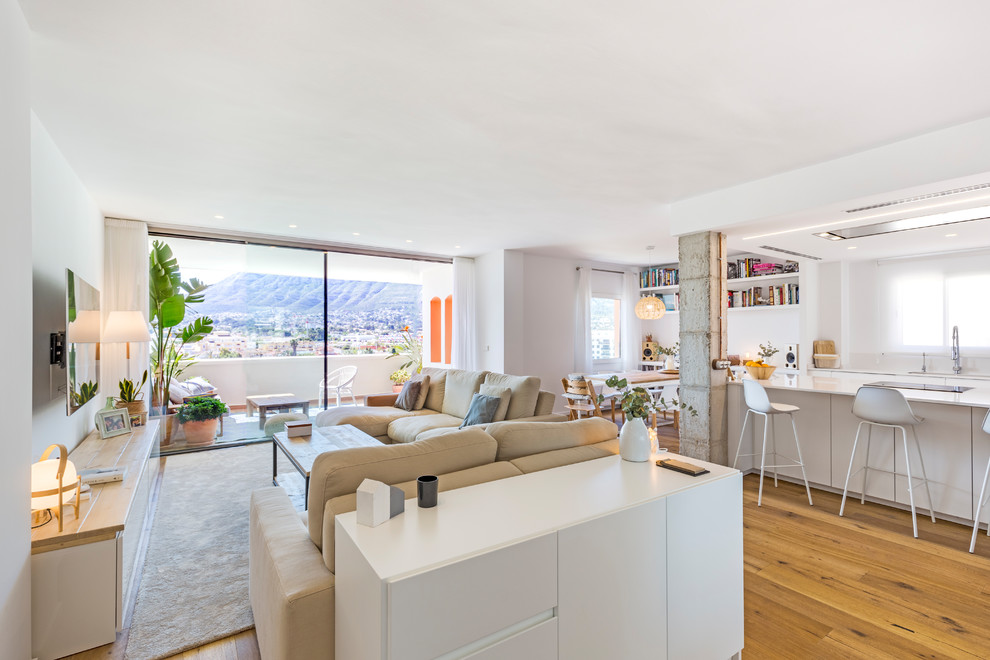 Esempio di un grande soggiorno minimal aperto con pareti bianche, pavimento in legno massello medio, TV a parete e pavimento marrone