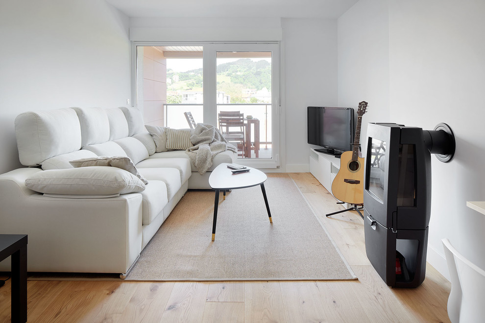 Foto de salón contemporáneo con paredes blancas, suelo de madera clara, televisor independiente y suelo beige