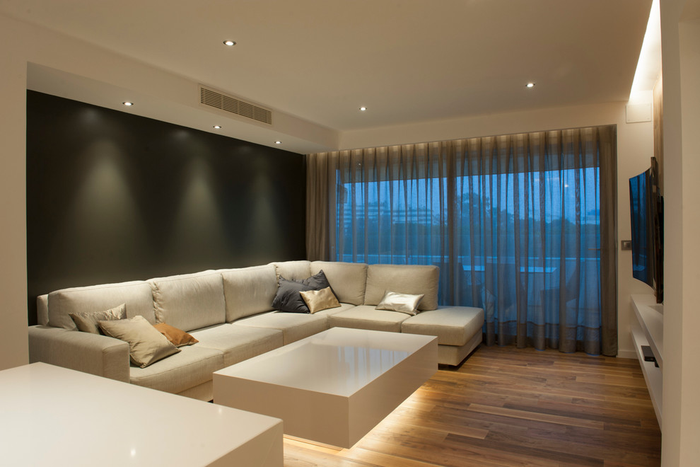 Modelo de salón para visitas abierto minimalista de tamaño medio sin chimenea con paredes multicolor, suelo de madera en tonos medios y televisor colgado en la pared