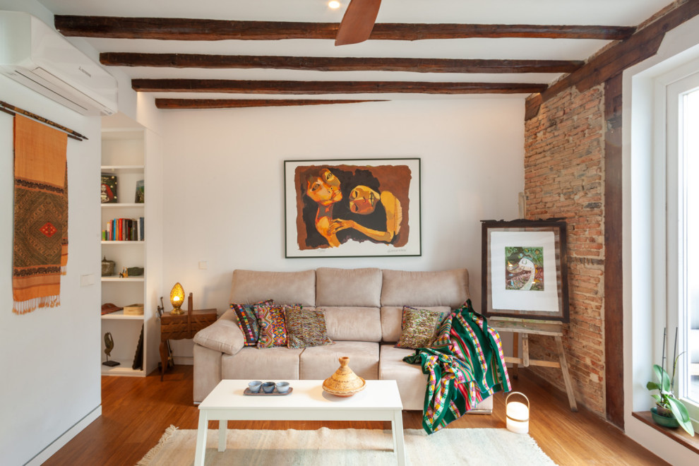 Imagen de salón mediterráneo con paredes blancas, suelo de madera en tonos medios, suelo marrón, vigas vistas y ladrillo