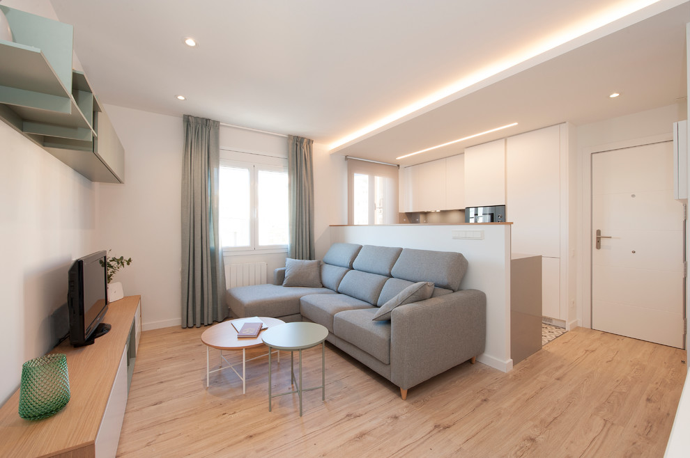 Foto de salón abierto escandinavo de tamaño medio con paredes blancas, suelo de madera clara, televisor independiente y suelo marrón