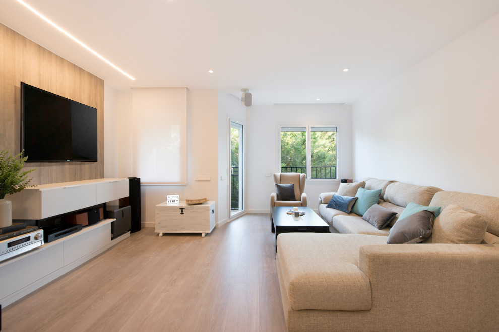 Imagen de salón abierto contemporáneo de tamaño medio sin chimenea con paredes blancas, suelo laminado, televisor colgado en la pared y suelo beige
