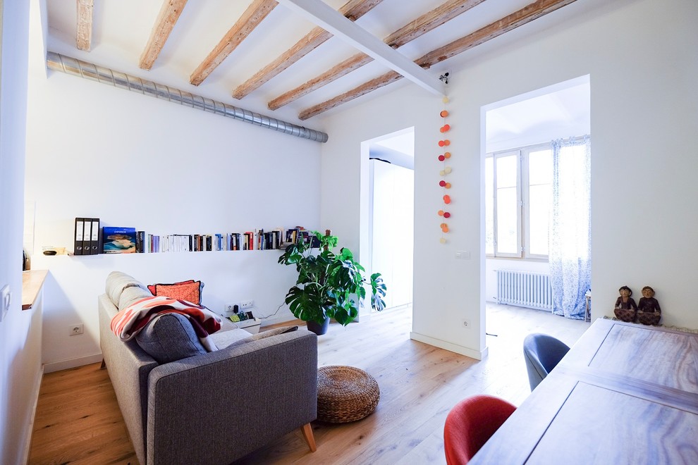 Diseño de biblioteca en casa abierta nórdica de tamaño medio sin televisor con paredes blancas, suelo de madera clara y suelo marrón