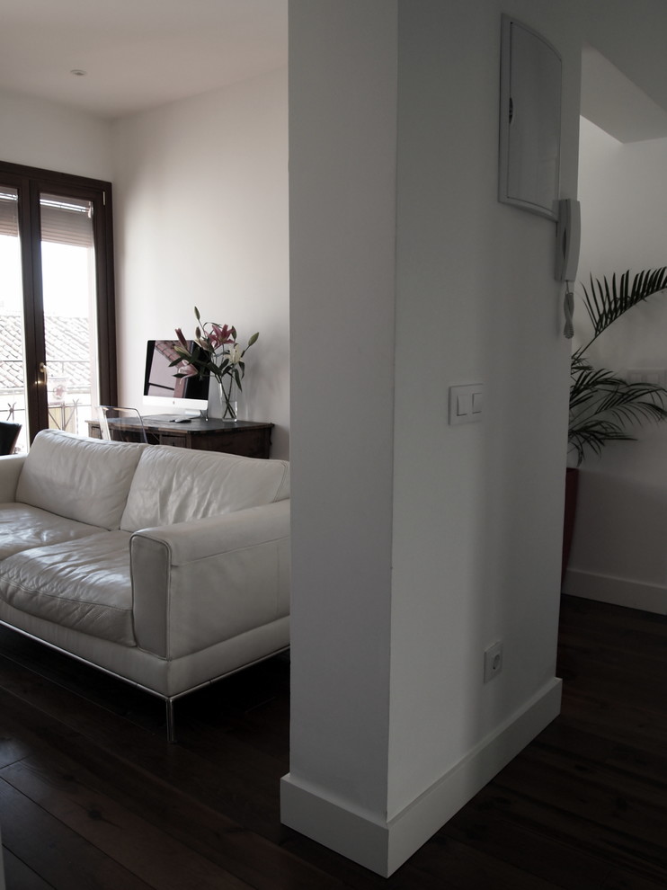 Modelo de salón minimalista con paredes blancas, suelo de madera oscura y suelo marrón