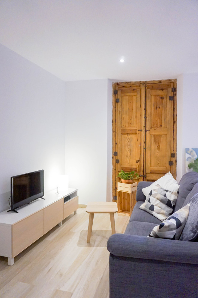 Diseño de salón abierto minimalista de tamaño medio con paredes blancas, suelo de madera clara, televisor independiente y suelo beige