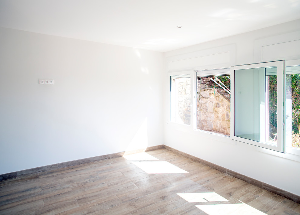 Großes, Offenes Modernes Wohnzimmer ohne Kamin mit weißer Wandfarbe, Keramikboden und braunem Boden in Barcelona