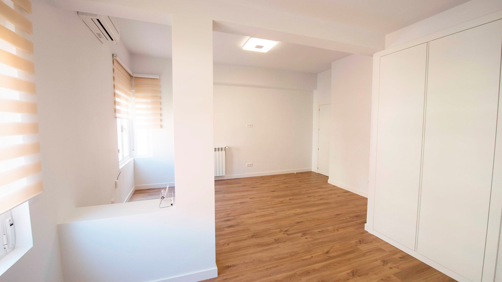 Modelo de salón cerrado minimalista con paredes blancas, suelo de madera en tonos medios y suelo marrón